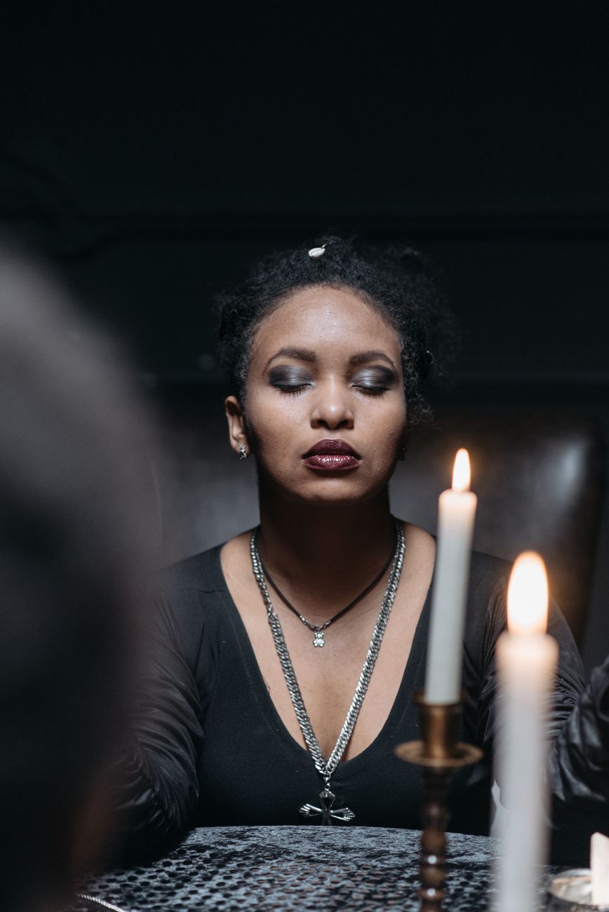 a woman doing ritual with her eyes closed near lighted candles